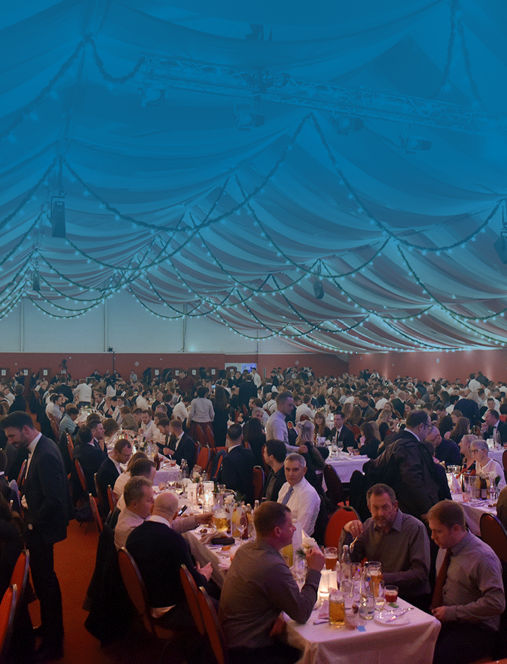 Many people sit in a large tent at the ODU Christmas party.