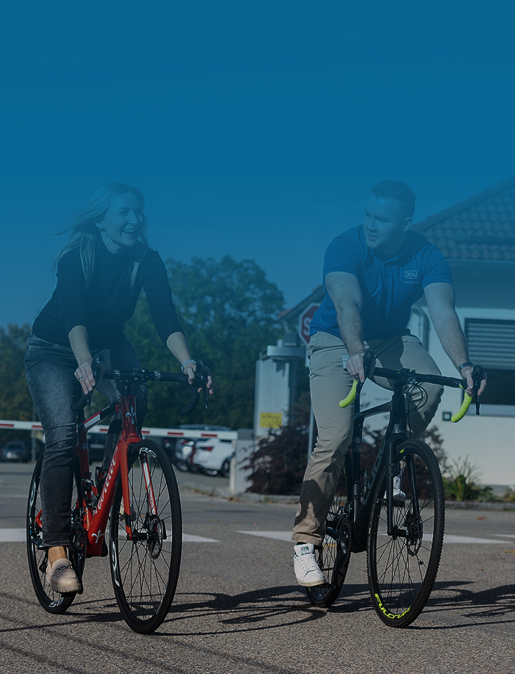 A woman and a man ride bicycles on the ODU company premises.